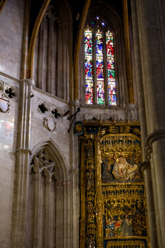 A gilded altarpiece rises beneath a tall stained glass window in Oviedo Cathedral Spain 