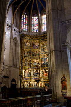 A golden reredos rises beneath colorful stained glass windows in Oviedo Cathedral Spain 