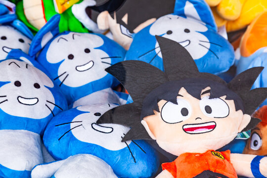 Frankfurt, Germany - May 15, 2026: Pile of plush toys of Son Goku from Dragon Ball anime and blue cat characters at a fairground stall