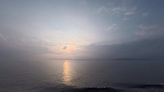 Cinematic real-time video of a bright sun over the horizon with a beautiful reflection path on the ocean