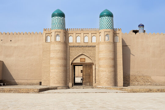 Kunya Ark citadel gate with turquoise-domed towers in Ichan Kala, Khiva, Uzbekistan. Symmetrical fortified entrance ideal for travel guides, history publications, and tourism brochures.