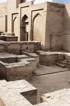 Ancient brick ruins and excavated foundations inside Ichan Kala in Khiva, Uzbekistan. Weathered brickwork with pointed arches and herringbone paving in the historic walled city. Ideal for travel.