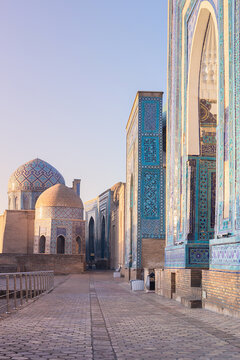 Shah-i-Zinda necropolis in Samarkand with ornate turquoise-tiled mausoleums along an empty cobblestone pathway at golden hour. Ideal for travel, cultural heritage publications, and tourism brochures.