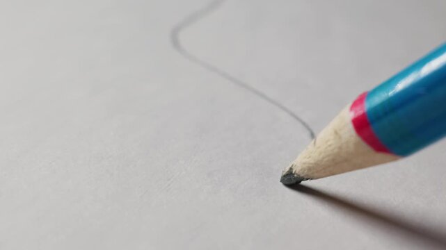 A detailed macro view of a striped pencil drawing a curved graphite line on white textured paper. Concept of creativity, graphic design, artistic expression, starting a project, and education.