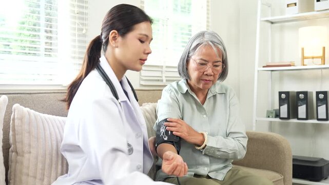 Female doctor performing a routine health check on a smiling senior woman during a home healthcare visit in a comfortable living room.