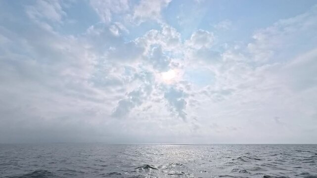 Stunning maritime landscape featuring a high sun through dramatic clouds and silver sea ripples