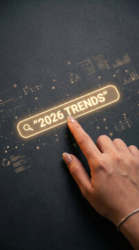 Finger interacting with a glowing search bar displaying "2026 TRENDS" on a dark, textured background, symbolizing foresight and digital exploration of future market insights