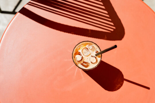 Top view of cold iced espresso tonic on a terracotta table with harsh shadows