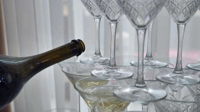 The waiter pours champagne into a crystal pyramid.
