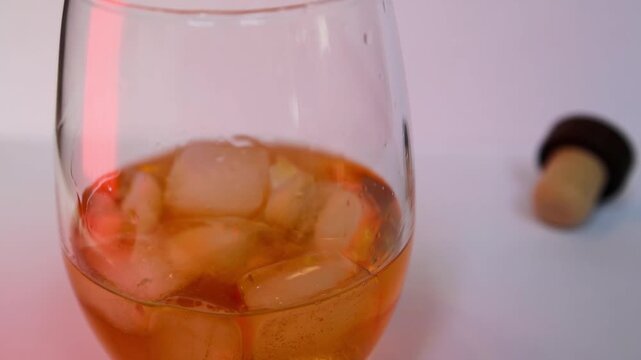 Filled whiskey glass with ice. Whiskey or Rum in glass served over ice, on the rocks. Amber whiskey, rum, or bourbon served on ice in stemless glass