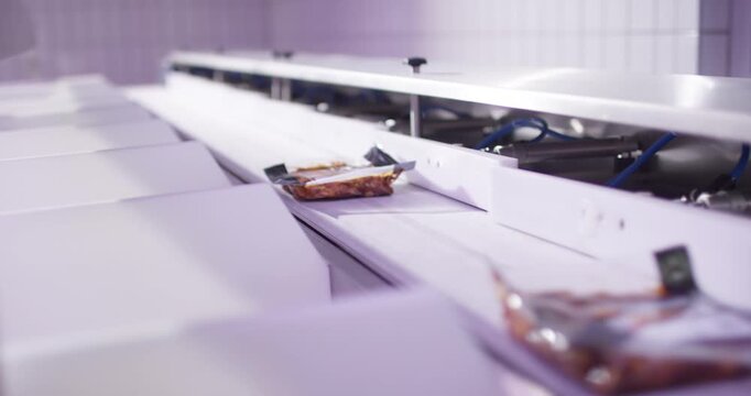 Sealed food tray moves along a white packaging conveyor