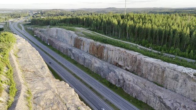 Backward Diagonal Drone Flight Over Highway Rock Cut at Sunset, Finland