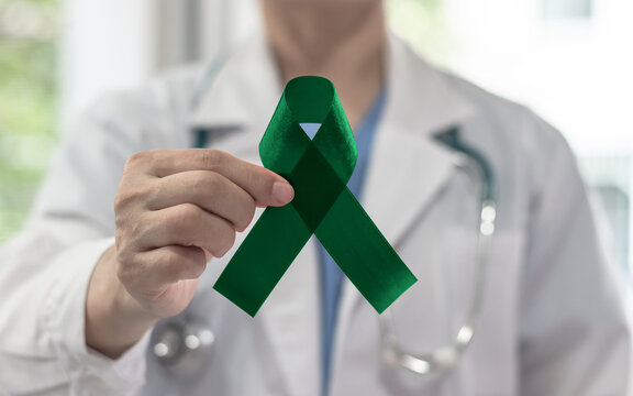 Jade Green (Emerald) ribbon awareness color for Liver Cancer and Hepatitis B - HBV month, bow on doctor's hand support medical background
