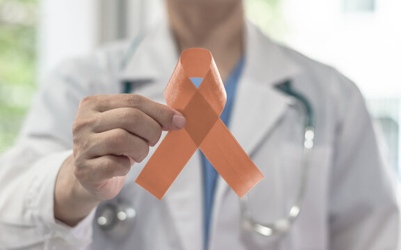 Uterine, Gynecologic, Endometrial and Vaginal Cancer awareness ribbon with peach bow color on doctor's hand support, hospital background in September month