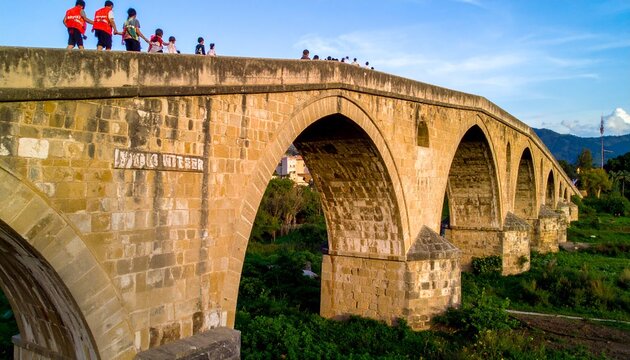 Ancient stone arch bridge over a serene river valley.