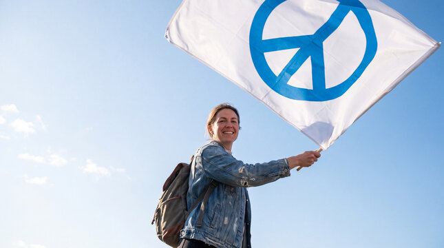 Woman holding peace symbol flag against a clear blue sky