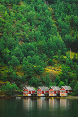 Fototapeta premium Classic red Norwegian boathouses along the edge of the fjord. Sognefjord port in Flam, Norway. Red wooden Docks in small tourist town of Flam on western side of Norway deep in fjords.