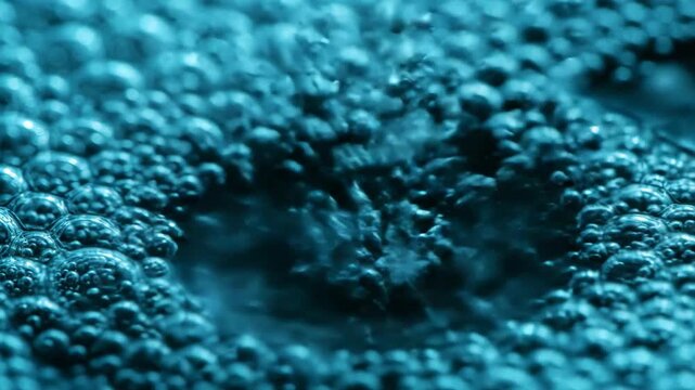 Blue water bubbles forming and bursting on liquid surface in macro close up for science and nature content