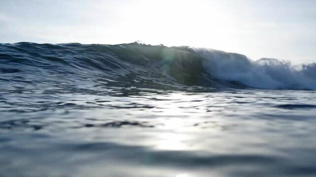 Ocean wave rolling and crashing toward camera at water level for surf and nature content