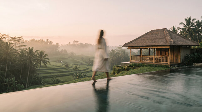 Woman Walking on Luxury Villa Terrace Overlooking Rice Fields at Sunrise