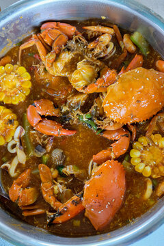 Delicious Indonesian-style seafood boil in a pot with whole mud crabs, clams, shrimps, and corn on the cob, perfect for a feast