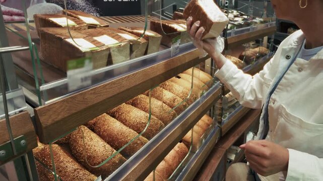 Customer Taking Fresh Loaf Of Bread From Bakery Shelf In Supermarket. Choosing Baked
