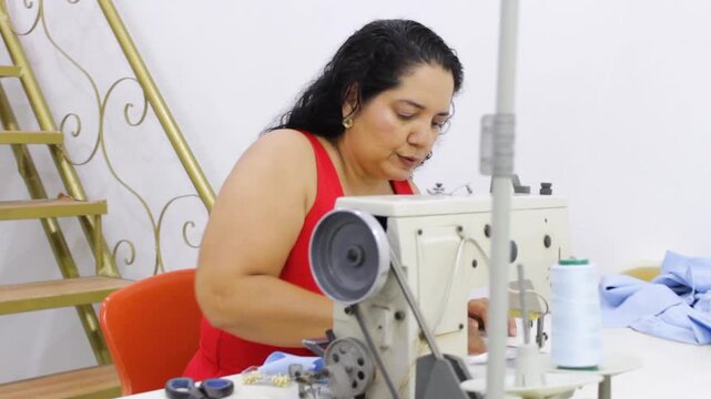 A seamstress is dusting a sewing machine with a cloth on a table in a sewing room in Neiva, Huila, Colombia. Concept of hygiene and businesswoman