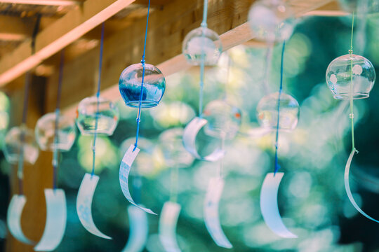 Japanese glass wind chimes hanging under a wooden roof in summer