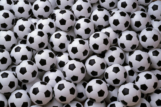 Many soccer balls piled together on a surface