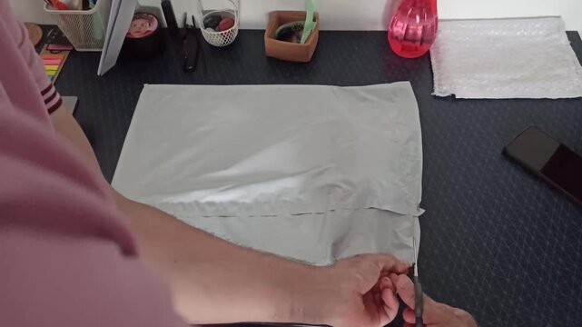 Flat lay of a white padded envelope on a desk with office supplies and a smartphone