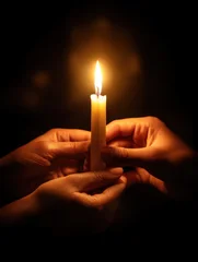 Three young smooth hands holding a glowing candle, universal symbol of interfaith prayer, peace and unity © britaseifert