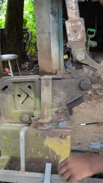 Manual metal rod cutter operating in industrial workshop