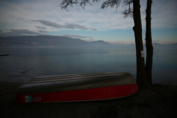 Upside-down red rowing boat on a misty lakeshore in Lombardy, Italy © ClaudioArnese