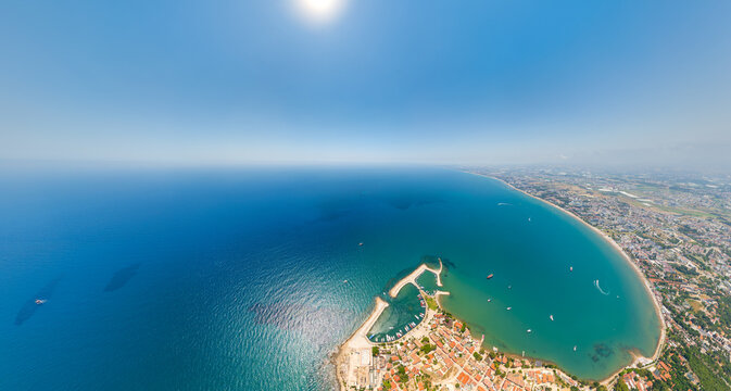 Side, Manavgat, Turkey. Panoramic aerial shot of Mediterranean coastline, beaches, modern Side town and ancient archaeological site on peninsula. Aerial view