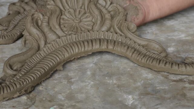 Artisan sculpting clay ornaments for traditional idol making
