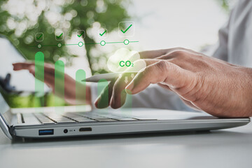 Business professional monitoring carbon reduction performance and CO2 emissions, laptop and tablet with sustainability dashboard, ESG compliance checklist, net zero strategy, green business technology © LAONG