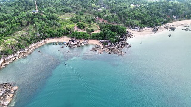 Cinematic Aerial View of Turun Aban Beach Sungailiat Bangka Featuring Turquoise Ocean, Granite Coastline, Hidden Bays and Tropical Paradise