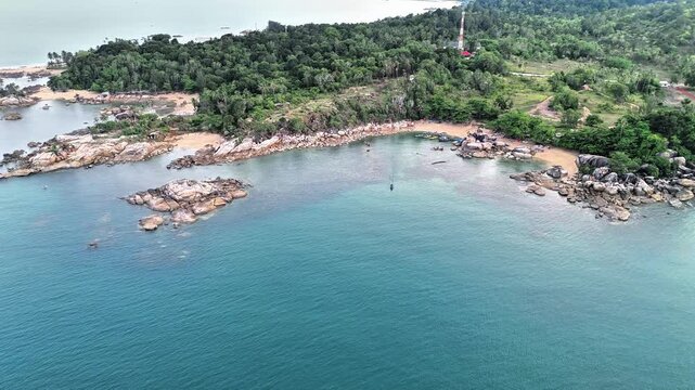 Cinematic Drone View of Turun Aban Beach Sungailiat Bangka Featuring Granite Coastline, Crystal Clear Water and Peaceful Tropical Bay Paradise