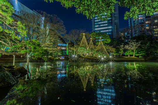 Night view of illuminated Yukitsuri and reflections with Tokyo Dome and buildings in the background at Koishikawa Korakuen January 2024