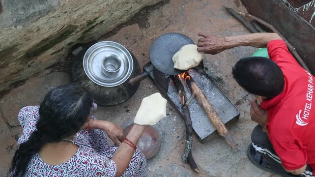 Raw video footage of village women making traditional roti together on a wood-fired stove in Uttarakhand, India, showcasing rural cooking, village life, and poverty.