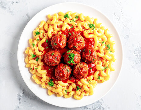 Elbow macaroni topped with meatballs and red sauce, white plate, top view. AI