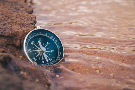 The compass by the river in the forest is a symbol of travel.