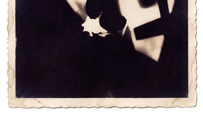 Vintage sepia toned photograph showing a mysterious shadow cast upon a textured aged paper surface edge