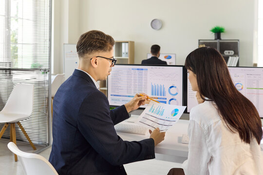 Analysts discuss data analytics and finance dashboard. Professional teamwork reviews charts on computer in a modern office, covering accounting and investment. Data led team decision concept.