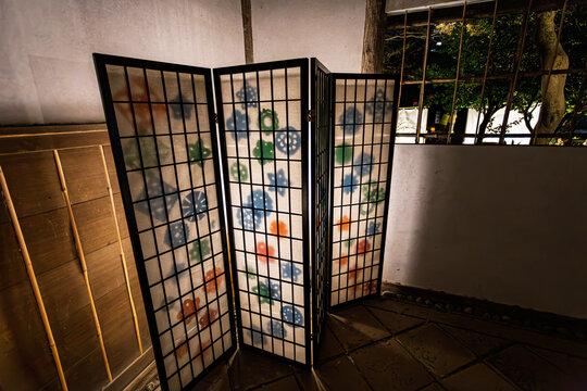A traditional Japanese screen with glowing colorful paper-cut patterns illuminated at night in Koishikawa Korakuen January 2024