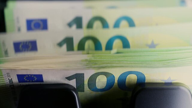 Euro banknotes passing through an automatic money counter before currency exchange. International finance, travel money and foreign exchange services.