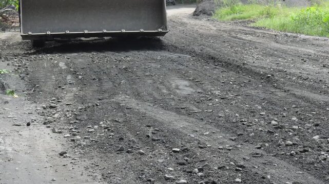 Excavator bucket shaping rugged road surface
