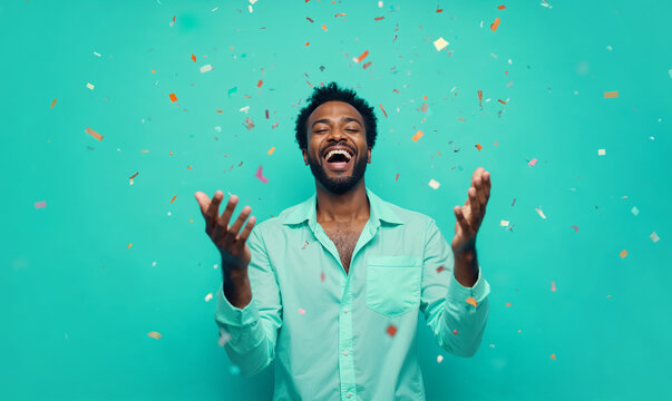 Man celebrating joyfully under falling confetti on teal background.