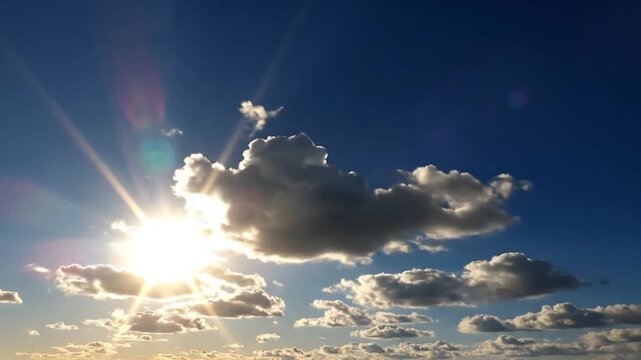 Bright sun rays shining through white clouds in a blue sky