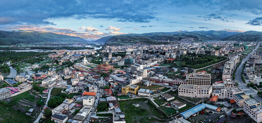 Aerial panoramic view of Garzê County at sunrise, Tibetan town by Yalong River, Garzê Temple white stupa, mountain plateau city morning landscape in West Sichuan © Deng Xuejun